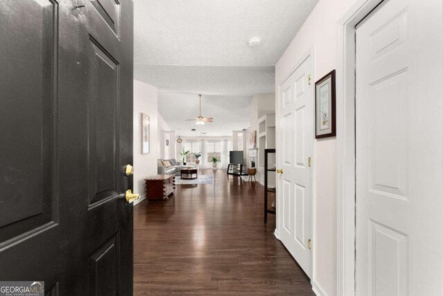 foyer with a textured ceiling, ceiling fan, and dark wood-type flooring