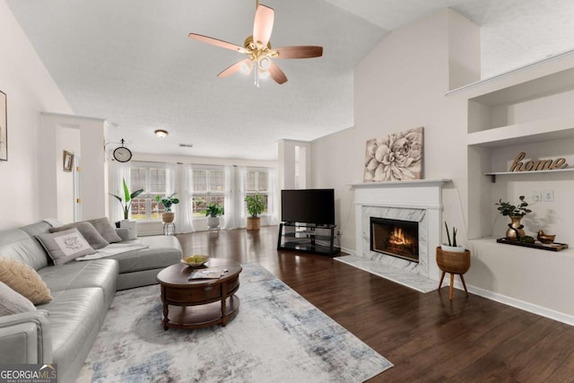 living room featuring ceiling fan, a high end fireplace, lofted ceiling, and hardwood / wood-style flooring