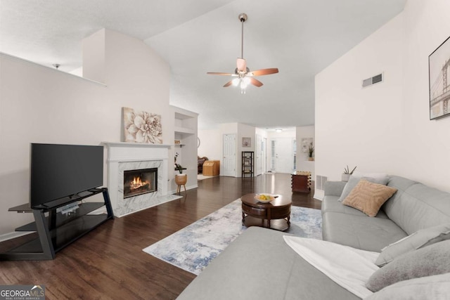 living room featuring ceiling fan, lofted ceiling, dark wood-type flooring, and a premium fireplace