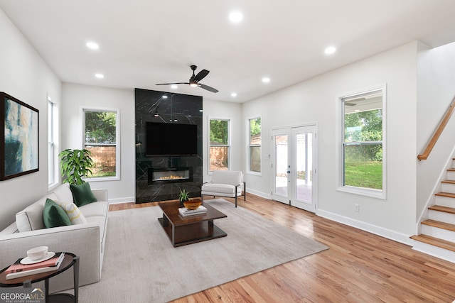 living room with ceiling fan, light wood-type flooring, a wealth of natural light, and a premium fireplace