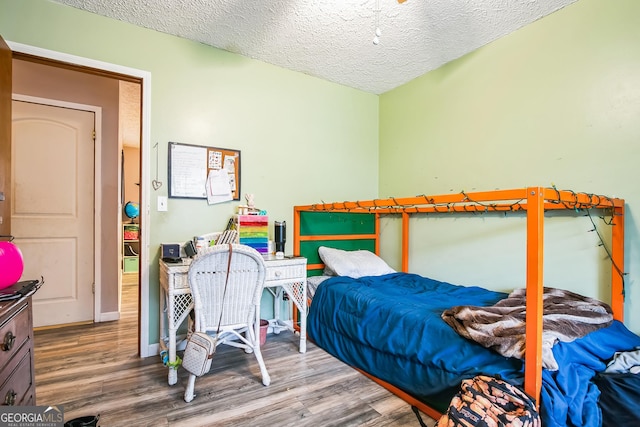 bedroom with a textured ceiling and hardwood / wood-style flooring