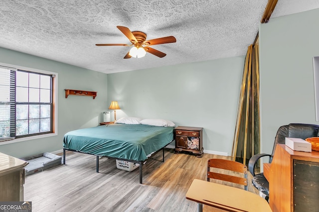 bedroom featuring ceiling fan, a textured ceiling, and light wood-type flooring