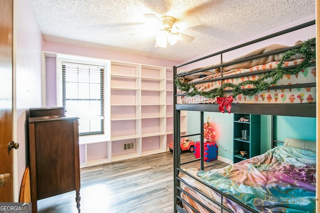 bedroom with hardwood / wood-style floors, a textured ceiling, and ceiling fan