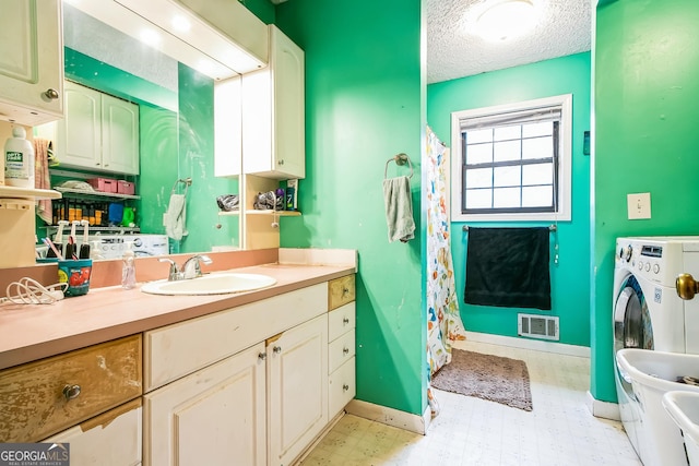 bathroom featuring vanity, a textured ceiling, and washer / dryer