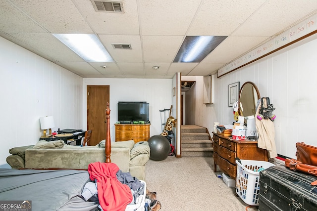 basement with a paneled ceiling, carpet floors, and wood walls