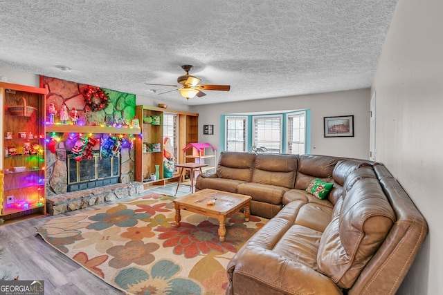 living room featuring a fireplace, a textured ceiling, hardwood / wood-style flooring, and ceiling fan