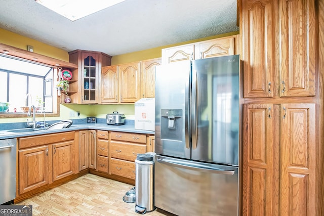 kitchen featuring sink, light hardwood / wood-style flooring, a textured ceiling, and appliances with stainless steel finishes