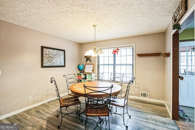 dining area featuring wood-type flooring, a textured ceiling, and an inviting chandelier