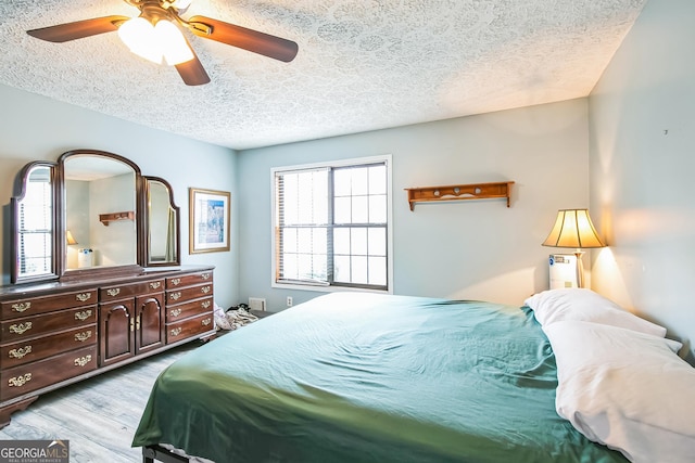 bedroom featuring ceiling fan, light hardwood / wood-style flooring, and a textured ceiling