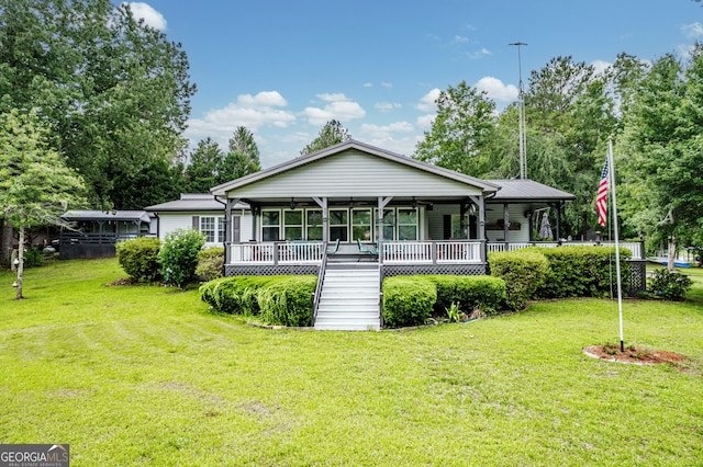 rear view of house featuring ceiling fan, covered porch, and a yard