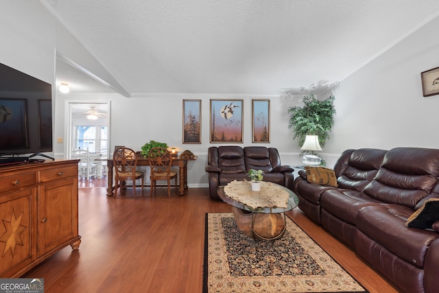 living room with a textured ceiling, dark hardwood / wood-style floors, crown molding, and lofted ceiling