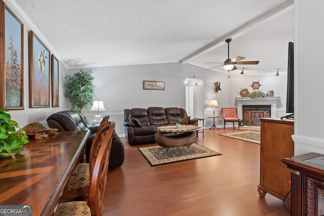 living room with lofted ceiling with beams, ceiling fan, wood-type flooring, and a textured ceiling