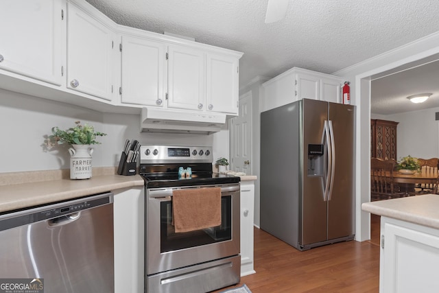 kitchen featuring a textured ceiling, stainless steel appliances, crown molding, white cabinets, and light hardwood / wood-style floors