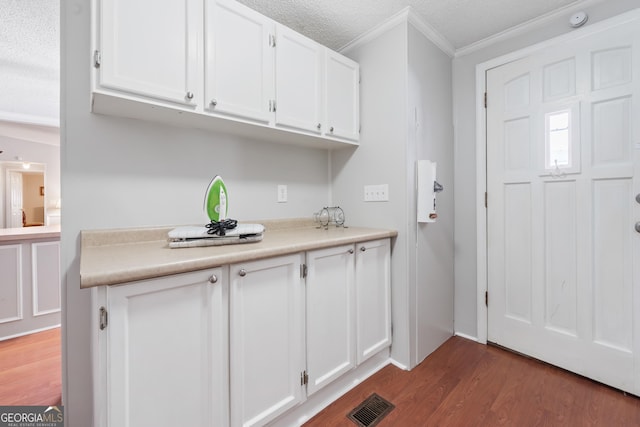 kitchen featuring a textured ceiling, crown molding, white cabinets, and dark hardwood / wood-style floors