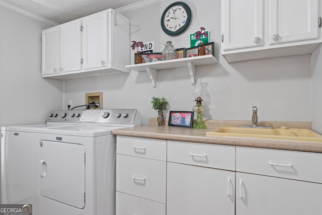 clothes washing area featuring cabinets, ornamental molding, a textured ceiling, sink, and washing machine and clothes dryer