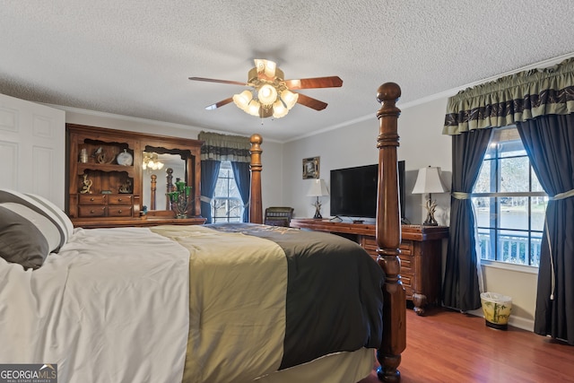 bedroom featuring ceiling fan, wood-type flooring, crown molding, and multiple windows