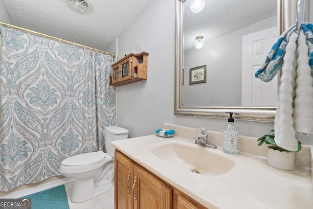 bathroom with tile patterned floors, vanity, a textured ceiling, and toilet