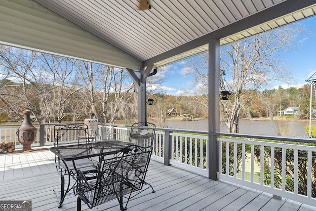 wooden terrace with a water view and exterior fireplace