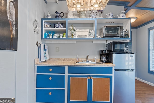 bar featuring blue cabinets, sink, ornamental molding, wood-type flooring, and stainless steel refrigerator