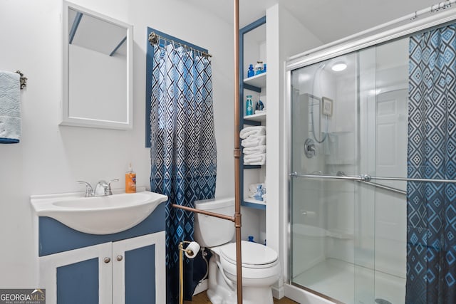 bathroom featuring a shower with door, vanity, and toilet