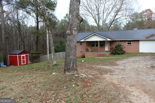 ranch-style home with a porch and a storage unit