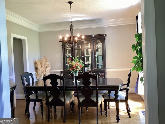 dining room featuring a chandelier, crown molding, wood finished floors, baseboards, and a textured ceiling