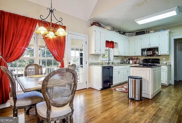 kitchen featuring black appliances, decorative light fixtures, and white cabinets