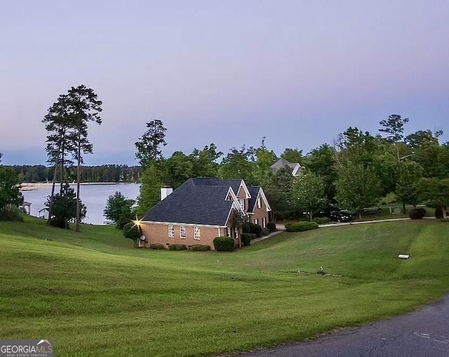 view of side of home with a water view and a yard