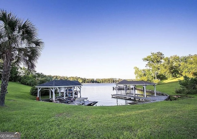 dock with boat lift, a water view, and a yard
