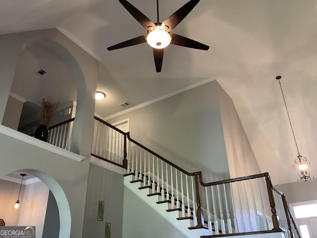 stairs with a ceiling fan, high vaulted ceiling, ornamental molding, and arched walkways