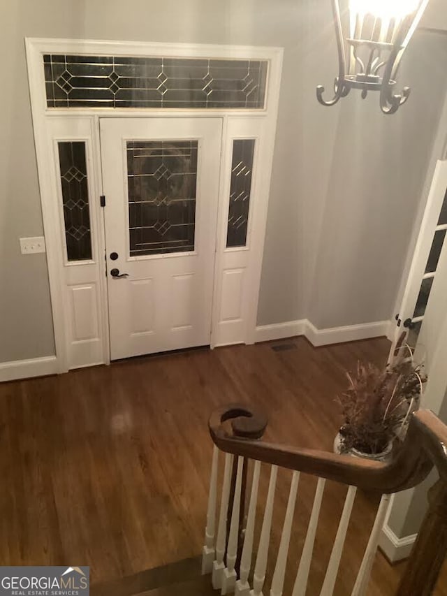 entrance foyer with dark wood-style flooring, baseboards, and a chandelier