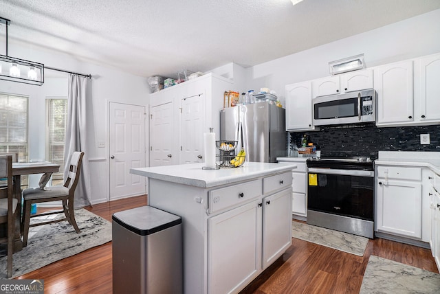 kitchen with a center island, decorative backsplash, stainless steel appliances, dark wood-style floors, and white cabinetry