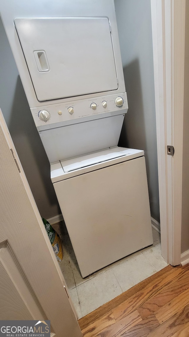 clothes washing area featuring light hardwood / wood-style flooring and stacked washer / dryer