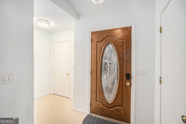 entryway featuring light colored carpet and a textured ceiling