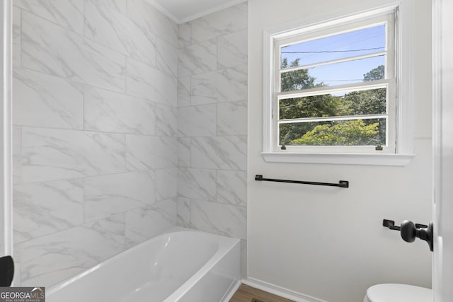 bathroom with toilet, wood-type flooring, and tiled shower / bath