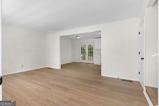 spare room featuring french doors and light wood-type flooring