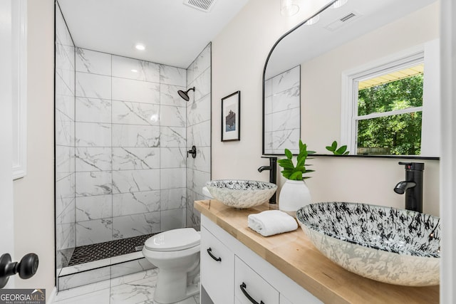 bathroom with toilet, vanity, and tiled shower