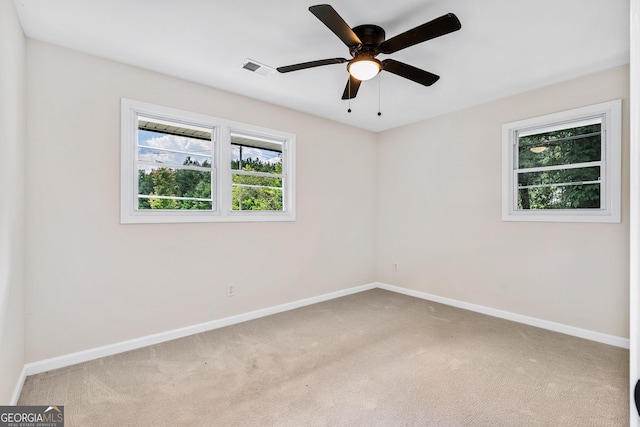 spare room featuring a wealth of natural light, ceiling fan, and light carpet