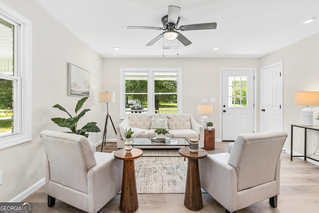 living room featuring light wood-type flooring, ceiling fan, and a healthy amount of sunlight