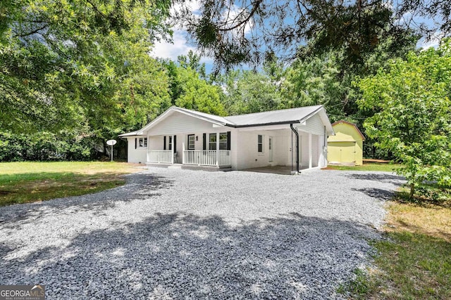 view of front of house featuring a porch, an outbuilding, a front yard, and a garage