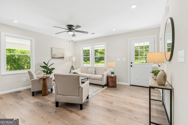 living room with light hardwood / wood-style floors, ceiling fan, and a healthy amount of sunlight