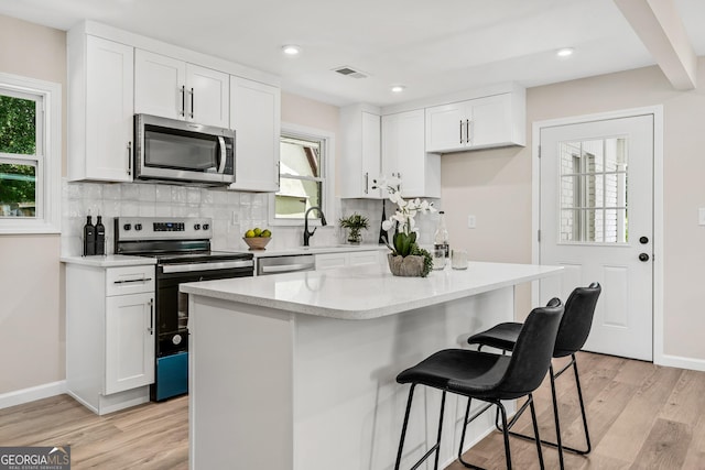 kitchen with a center island, a healthy amount of sunlight, stainless steel appliances, and white cabinetry