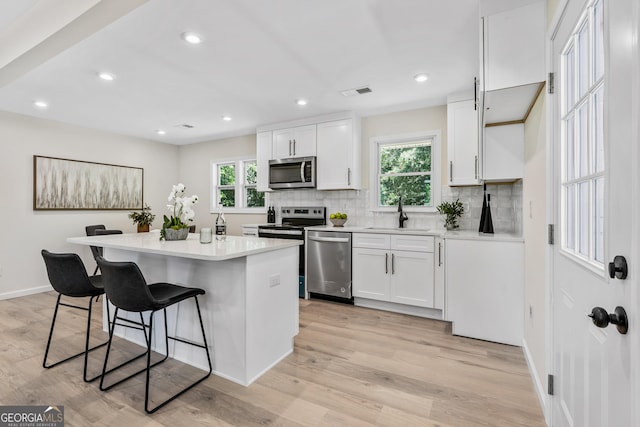 kitchen with white cabinets, appliances with stainless steel finishes, a healthy amount of sunlight, and sink