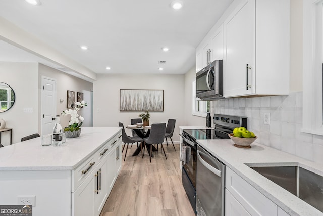 kitchen with white cabinets, appliances with stainless steel finishes, and plenty of natural light