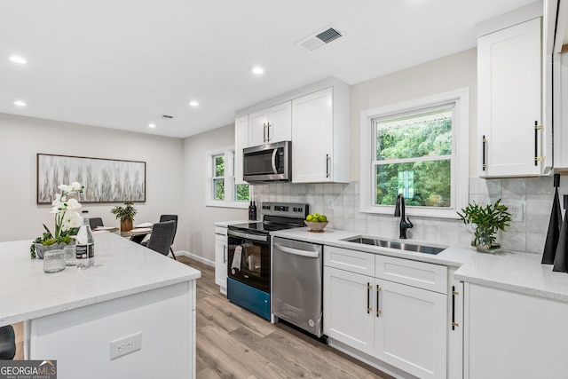 kitchen featuring a wealth of natural light, sink, white cabinets, and appliances with stainless steel finishes