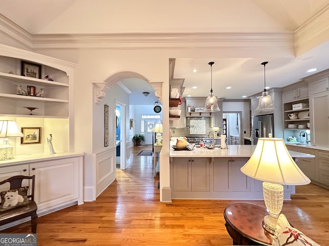 kitchen featuring kitchen peninsula, high end fridge, gray cabinetry, a kitchen breakfast bar, and hanging light fixtures