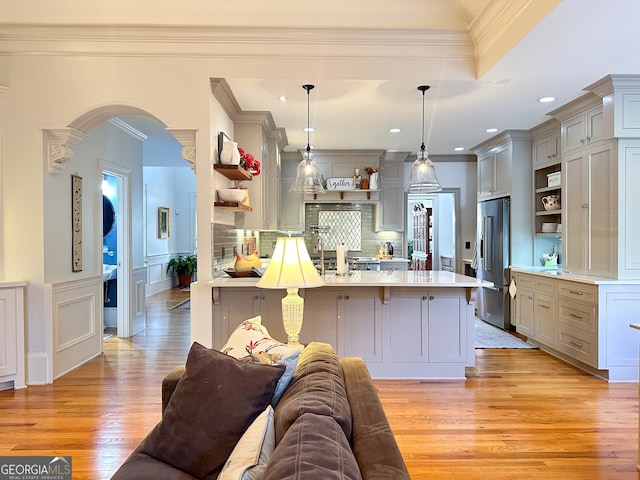 kitchen with light hardwood / wood-style floors, gray cabinets, a breakfast bar area, high end refrigerator, and hanging light fixtures