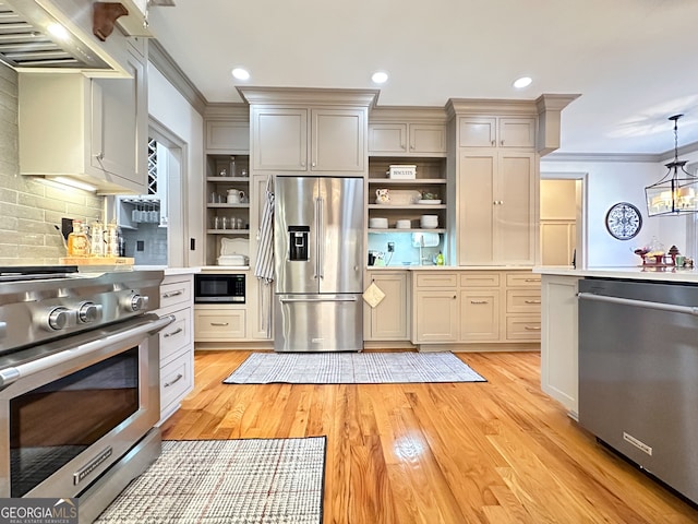 kitchen with premium appliances, tasteful backsplash, hanging light fixtures, wall chimney range hood, and light hardwood / wood-style flooring