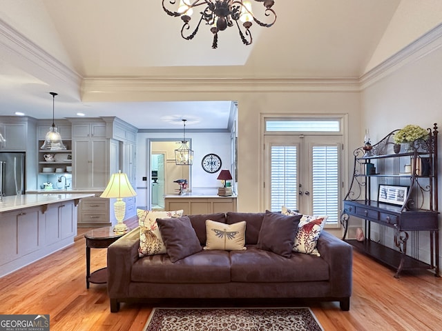 living room featuring french doors, an inviting chandelier, light hardwood / wood-style floors, ornamental molding, and vaulted ceiling