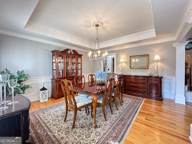 dining space featuring decorative columns, ornamental molding, and a raised ceiling